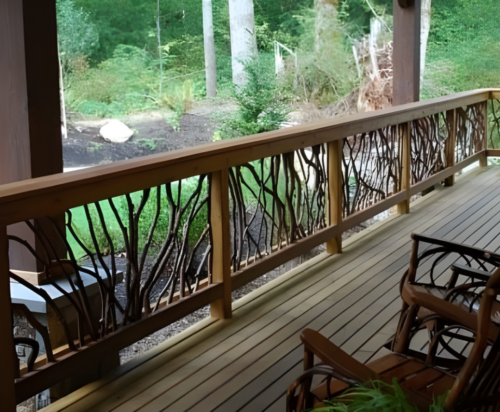 Wooden deck with handcrafted woven branch railing, wooden chairs, and a lush green forest view in the background.