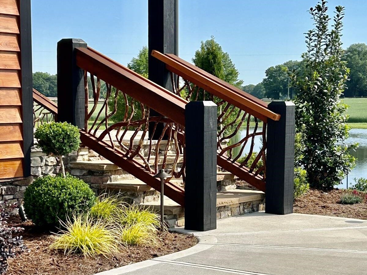 Dark custom exterior stair handrails in Charlotte, NC, with a scenic water view in the background, showcasing elegant design and craftsmanship.