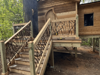 Cabin Entry with Split Staircase Design Wooden cabin with split staircase and woven branch railings built around a large tree.