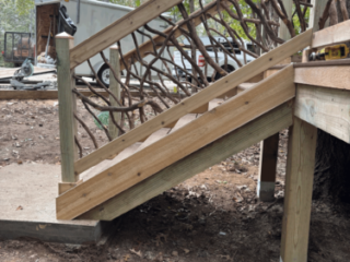 Deck Stairs with Natural Branch Detail Elevated deck stairs with decorative woven branch handrails in a forest setting.