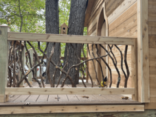 Woodland Deck with Branch Accents Wooden platform with decorative woven branch railing next to a cabin wall.