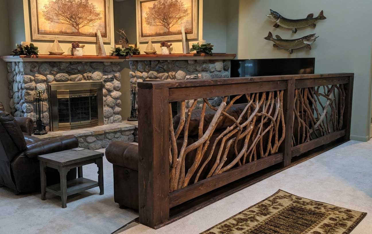 A stylish living room divider featuring a branch railing made of dark painted wood and natural laurel branches, enhancing the rustic decor.