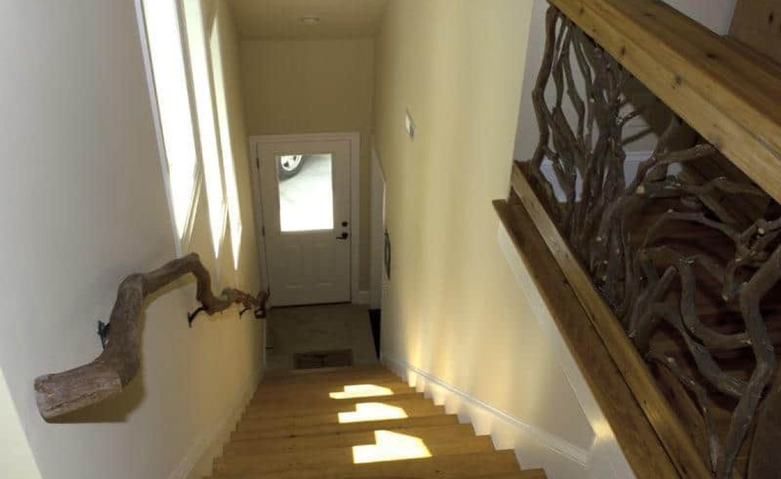 A branch banister descending the stairs, paired with a guardrail featuring Mountain Laurel handrails in a sunburst design.