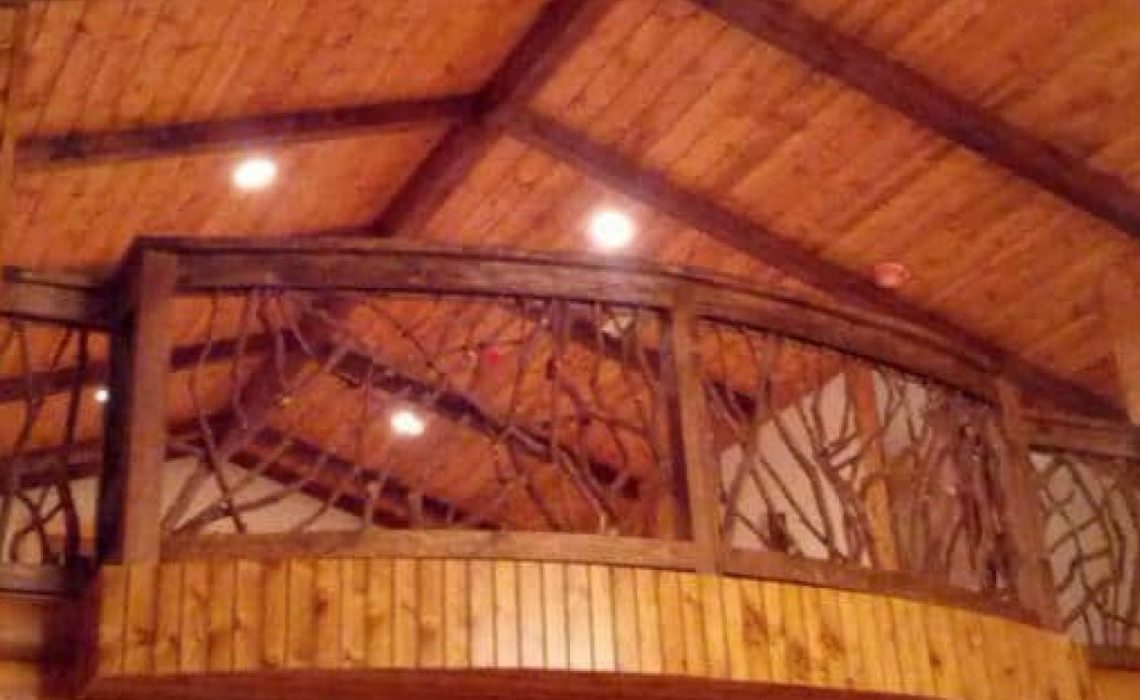 A product photo of a curved Mountain Laurel handrail installed indoors in a fully timber home.