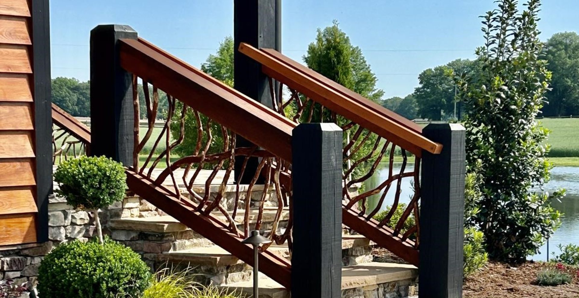 Dark custom exterior stair handrails in Charlotte, NC, with a scenic water view in the background, showcasing elegant design and craftsmanship.