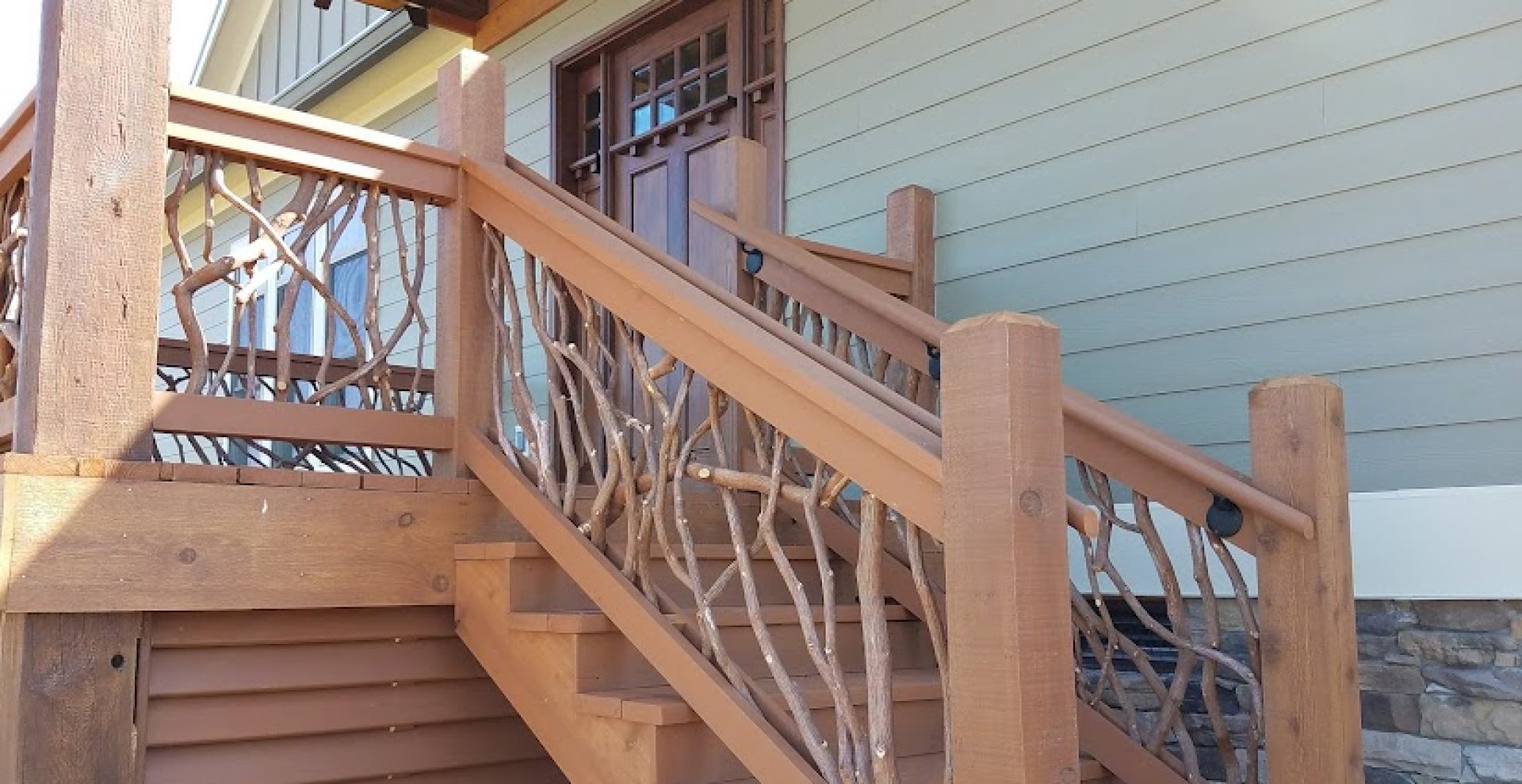 Brown porch stairs featuring mountain laurel branch balusters and sturdy handrails in Elizabethton, TN, creating a welcoming entrance.