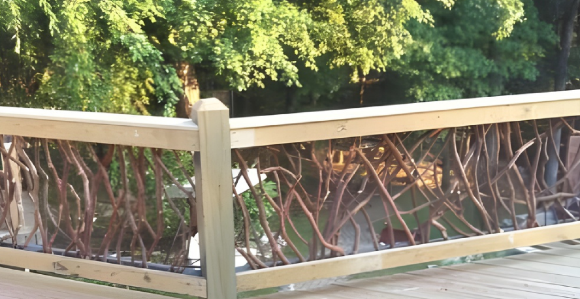 Wooden deck featuring a rustic woven branch railing with a lush green forest and pond in the background.