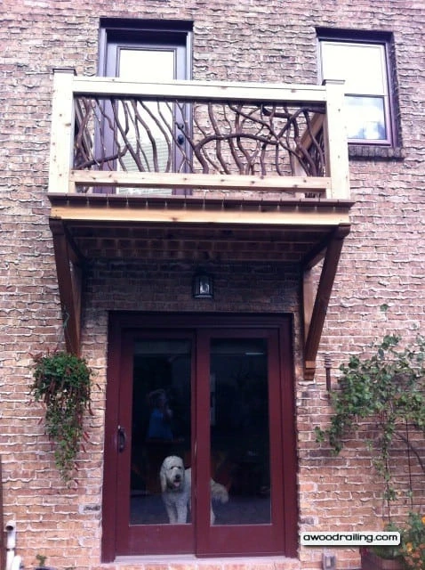 Juliet balcony railing with mountain laurel handrails and a dog visible below