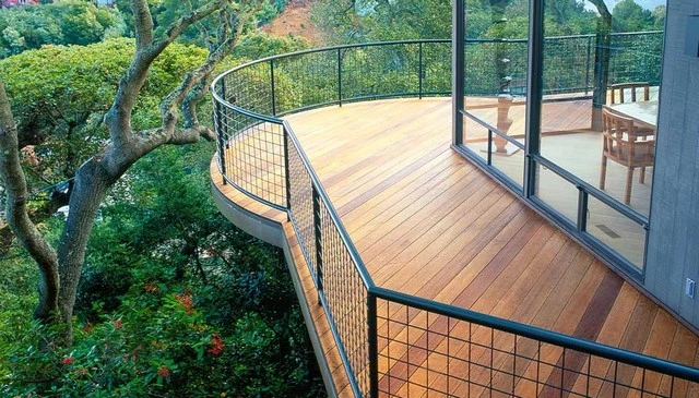 A minimalist black 4x4 wire metal grid featuring sleek black metal pipes on an Ipe wood deck, creating a modern aesthetic while floating among the trees.