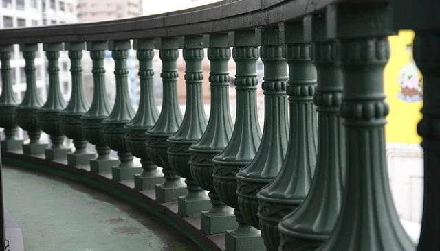 Heavily weighted stone balusters featuring a large diameter that shrinks to a fluted column top with studded ring detail for elegant deck railing design.