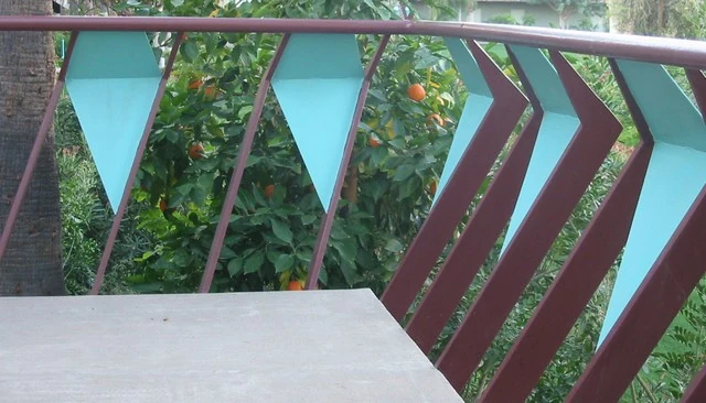 Cool deck railing design featuring angled metal balusters with light blue panels in alternating openings, creating a unique aesthetic for outdoor spaces.