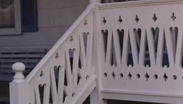 A decorative deck railing showcasing a sawn baluster design with a central row of alternating hearts and small crosses above and below, exemplifying charming outdoor aesthetics.
