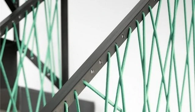 A metal angle loom with drilled holes showcasing a woven blue rope design, exemplifying customizable and inspiring railing solutions for outdoor spaces.