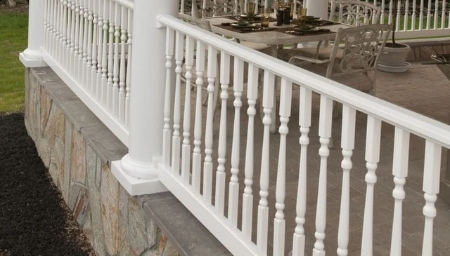 Contemporary turned balusters showcasing a slim design with strong symmetry for white patio railing, perfectly complementing a paver-floored porch exemplifying modern outdoor aesthetics.