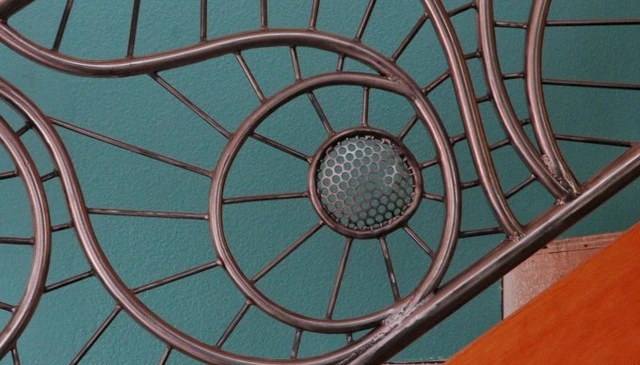 A custom metal pipe railing showcasing masterful metalwork with a fluid geometric design, exemplifying modern industrial style in outdoor architecture.