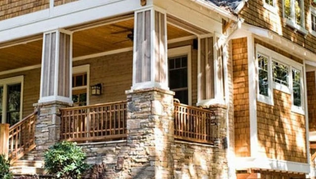 A porch step railing design showcasing stone post bases for mass and double horizontal elements that match the exterior woodwork exemplifying rustic outdoor aesthetics.