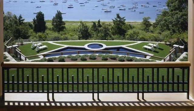 A Cape Cod home showcasing craftsman style metal railing with vertical and horizontal elements that emphasize spacing, overlooking the bay exemplifying coastal architectural beauty.