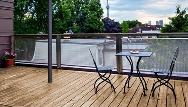 An invisible fine wire mesh railing showcasing long runs in framed openings that provide selective transparency in design exemplifying contemporary deck railing designs.