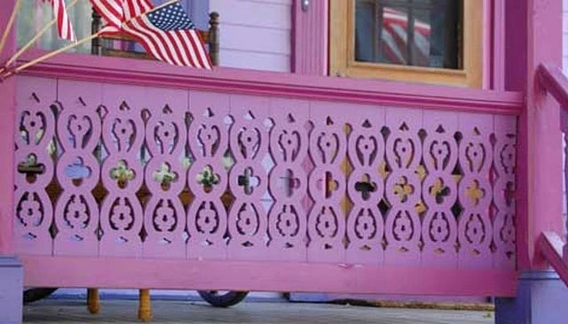 An intricate gingerbread deck railing design showcasing crosses, hearts, and diamonds in bright pink, perfect for a Victorian home remodel.