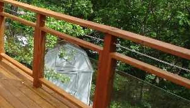 A mixed media design showcasing stained wood frames with glass panels and horizontal cable rail between double wood top plates, creating a modern and elegant railing solution.