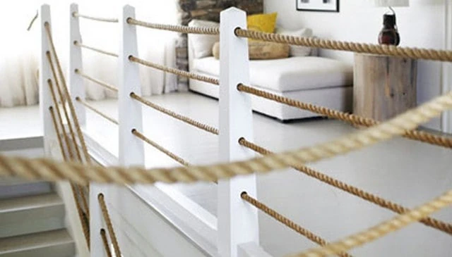 A horizontal rope railing design with tapering white-painted wood posts and a trim board, creating a cohesive and stylish look for outdoor spaces.