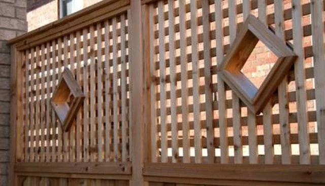 Custom wood lattice deck rails with diamond-shaped portholes and contrasting square patterns, showcasing a unique design that enhances outdoor aesthetics.