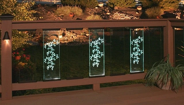 A glass baluster railing featuring LED lighted etched panels with a bold plant or vine design, creating a striking statement for outdoor spaces.