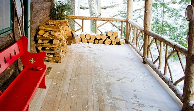 An inexpensive deck design showcasing simple elegance with open diamond-shaped railing and strong posts, ideal for a secluded log cabin setting.