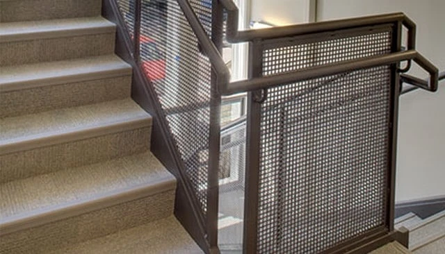 A deck privacy design showcasing metal mesh infill between square metal pipe posts, topped with a round pipe and complemented by a matching banister for innovative deck railing designs.
