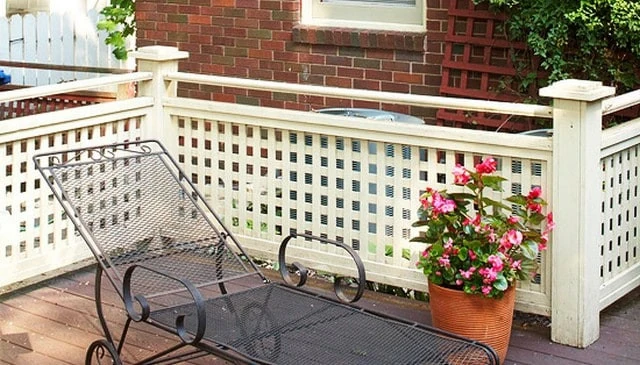 A charming porch railing design featuring a painted wood lattice guardrail with sturdy posts and a smooth 2x4 handrail for safety and comfort