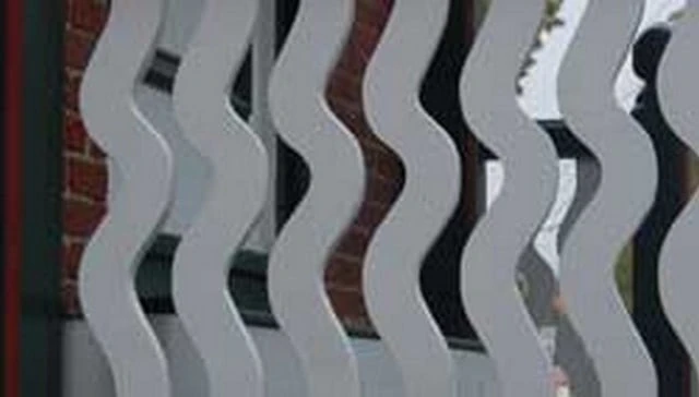 A captivating deck railing design featuring wavy vertical balusters with a unique sine wave pattern adding visual excitement to outdoor spaces