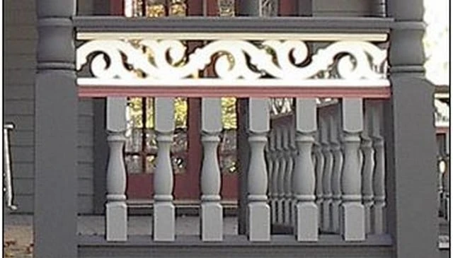 Charming porch handrail featuring an intricate jigsaw cut pattern over turned balusters, embodying a Victorian-inspired design for elegant deck railing design.