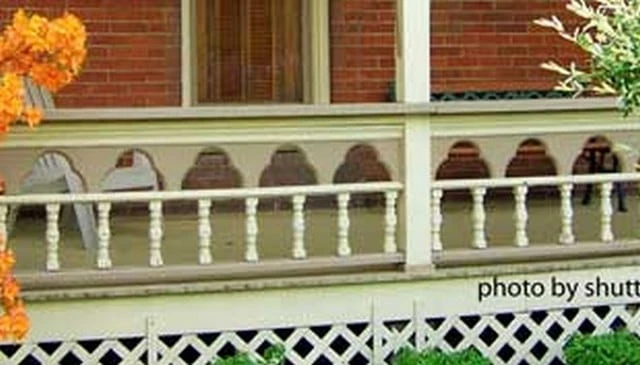 Elegant porch railings featuring intricate scroll saw cut patterns with triple-circle arches and delicate turned balusters for sophisticated deck railing design.