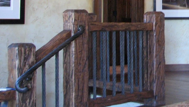 Reclaimed wood posts and railings complemented by large diameter vertical cables from a Colorado ski lift, creating a unique and rustic deck railing design.