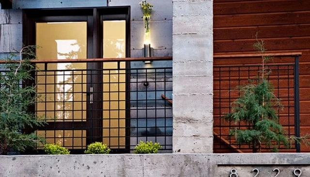 Contemporary front porch stoop railing featuring a square metal 4x4 grid with open space and a stained wood handrail for stylish deck railing design.
