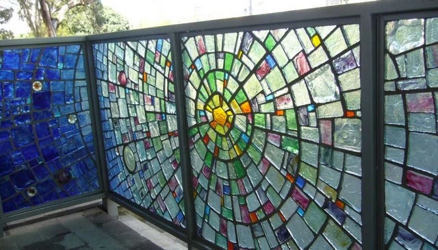 Stained glass railing design featuring a mandala-inspired circular pattern with radiating colors darkening from the center for vibrant deck railing design.