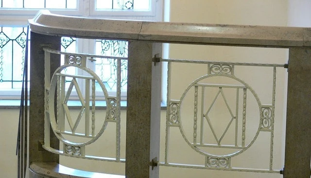Wrought iron panels featuring a circle and diamond pattern with a white finish, installed between granite 6-inch posts and below granite railing for deck railing design.