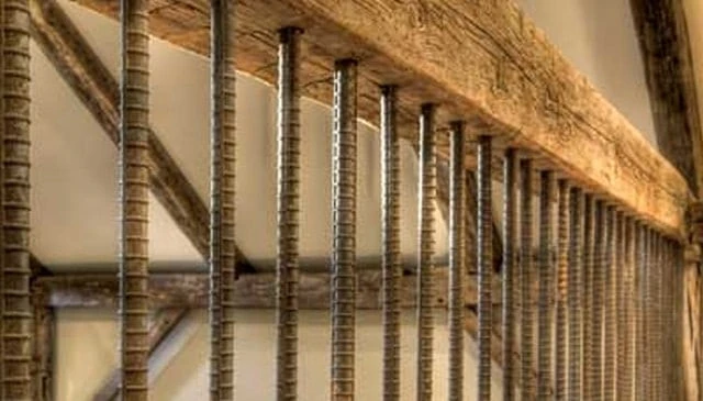 Rustic barnwood 4x6 beams featuring vertically spaced metal railing, ideal for a reclaimed wood timber frame home and unique deck railing designs.