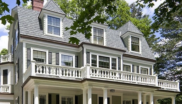 Colonial Revival home featuring a gambrel roof and elaborate cornice, complemented by elegant white trimmed turned baluster deck railing, ideal for classic deck railing designs.