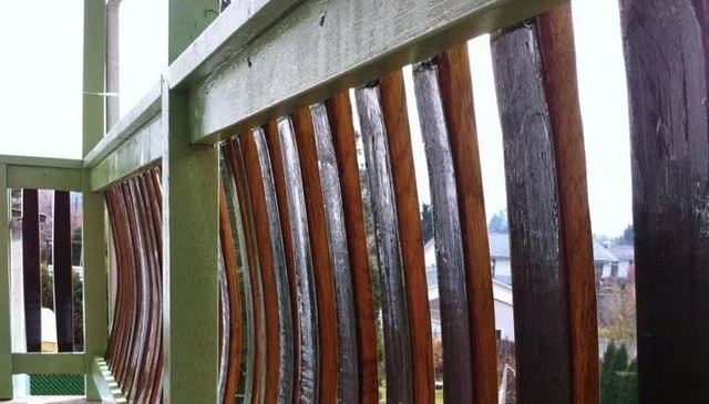 Wine barrel balusters featuring natural staves with green painted posts and lumber, designed for wine enthusiasts and outdoor spaces.