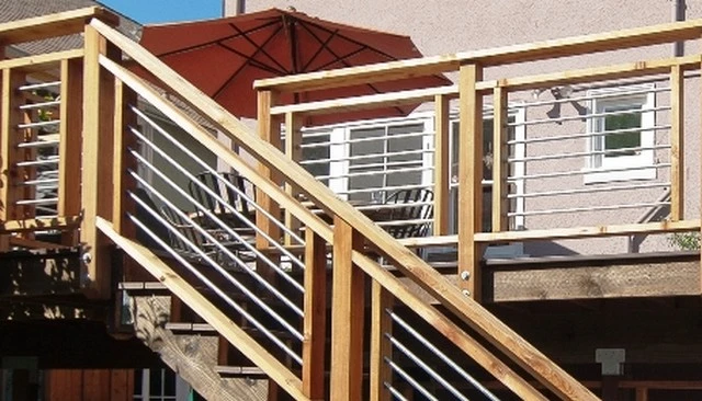 Picture frame style railing featuring horizontal metal pipes framed in unstained cedar, creating an appealing aesthetic for deck railing designs.