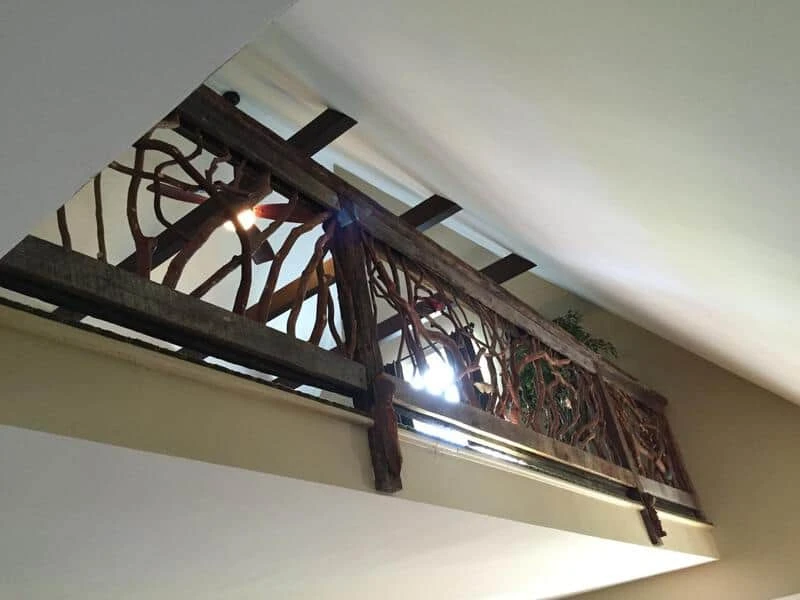 Carved birds in an upstairs balcony handrail surrounded by branches