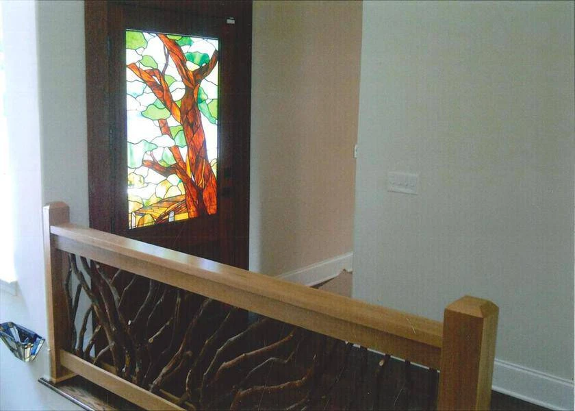 An indoor mountain laurel handrail featuring a sunburst branch design, complemented by premium oak boards and a glistening window.