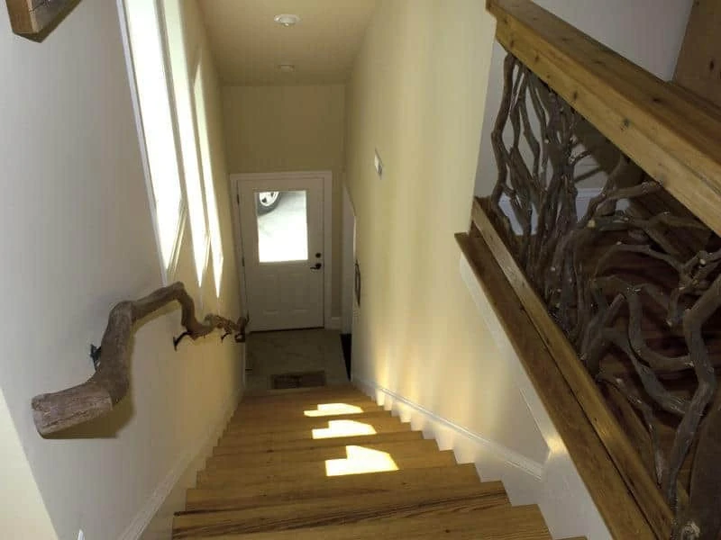 A branch banister descending the stairs, paired with a guardrail featuring Mountain Laurel handrails in a sunburst design.