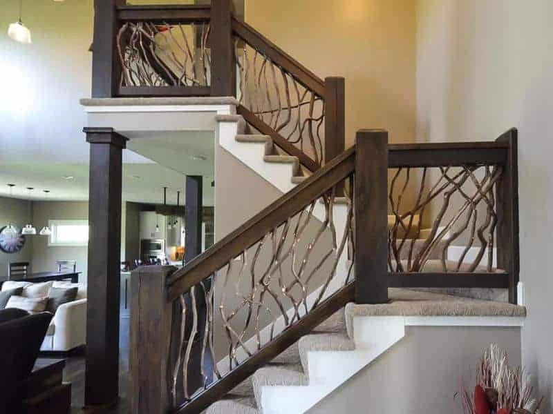 A product photo of indoor stair handrails featuring grey stained laurel branches against dark painted railings.