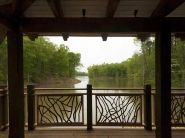 Lissara style handrails casting shadows on a dock porch overlooking a serene lake view.