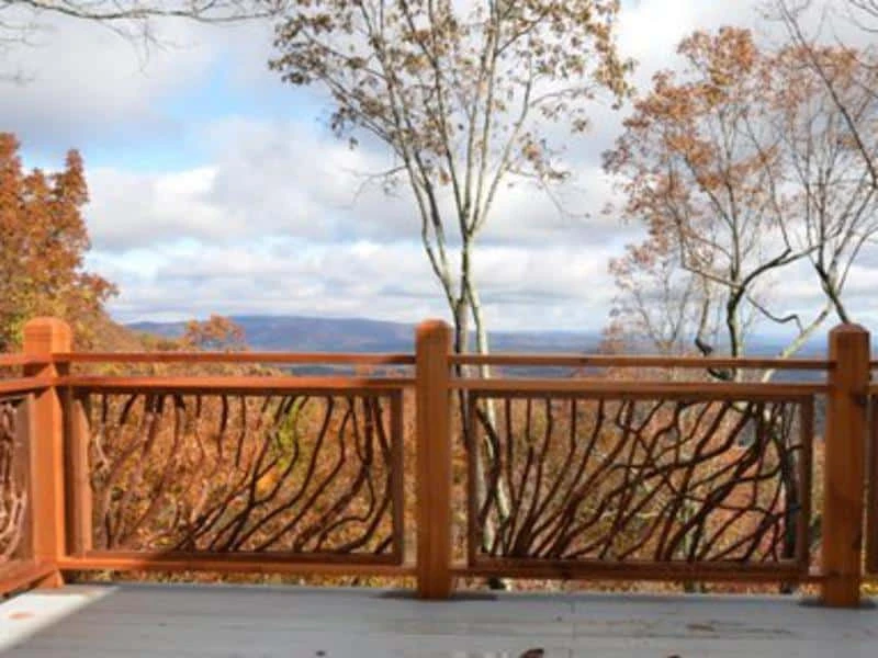 A Lissara style handrail featuring dark stained branches, with vibrant fall mountains visible in the background.