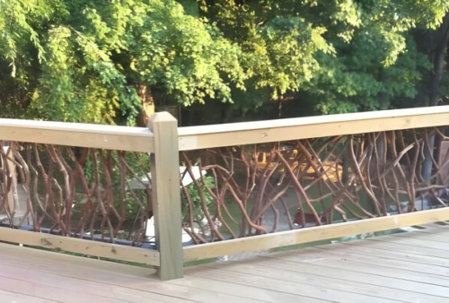 Wooden deck featuring a rustic woven branch railing with a lush green forest and pond in the background.