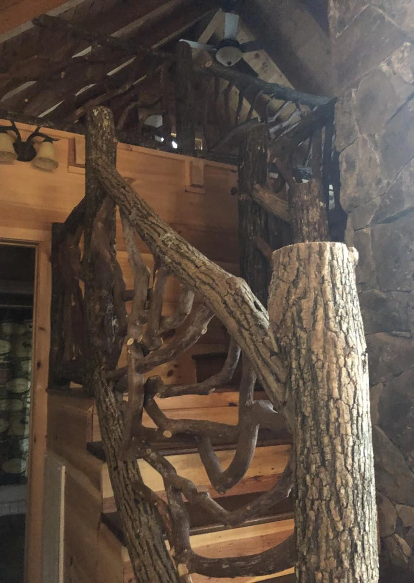 A rustic stair railing and posts made from locust logs with bark, showcasing natural textures and sturdy construction.