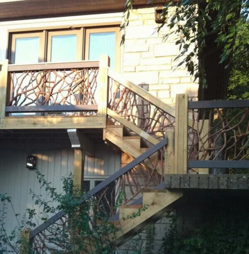 Wooden deck and staircase featuring decorative woven branch railings attached to a house exterior.